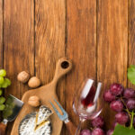Früchte und Wein auf Holztisch, Weintrauben, Käse, Nüsse, Weinglas, Weinelemente für Genuss, FHM Online Magazin.